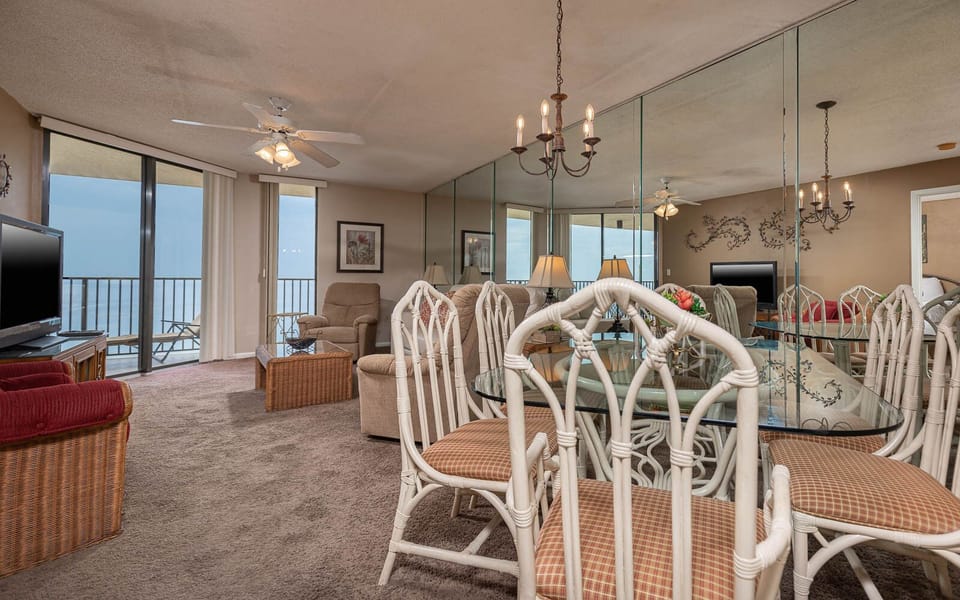 The inviting living area features a glass dining table, comfortable seating, and expansive views through large windows