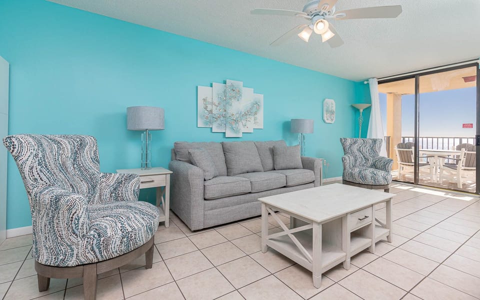 Cozy living area with a plush gray sofa with queen sleeper, stylish chairs, and a view of the beach