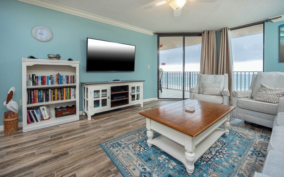 Unwind in the inviting living area, featuring plush seating, a large TV, and stunning beach views