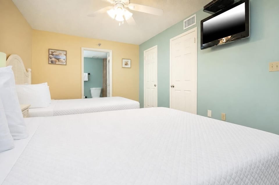 Relax in this guest bedroom featuring two queen beds, a TV, and soft colors that create a welcoming atmosphere