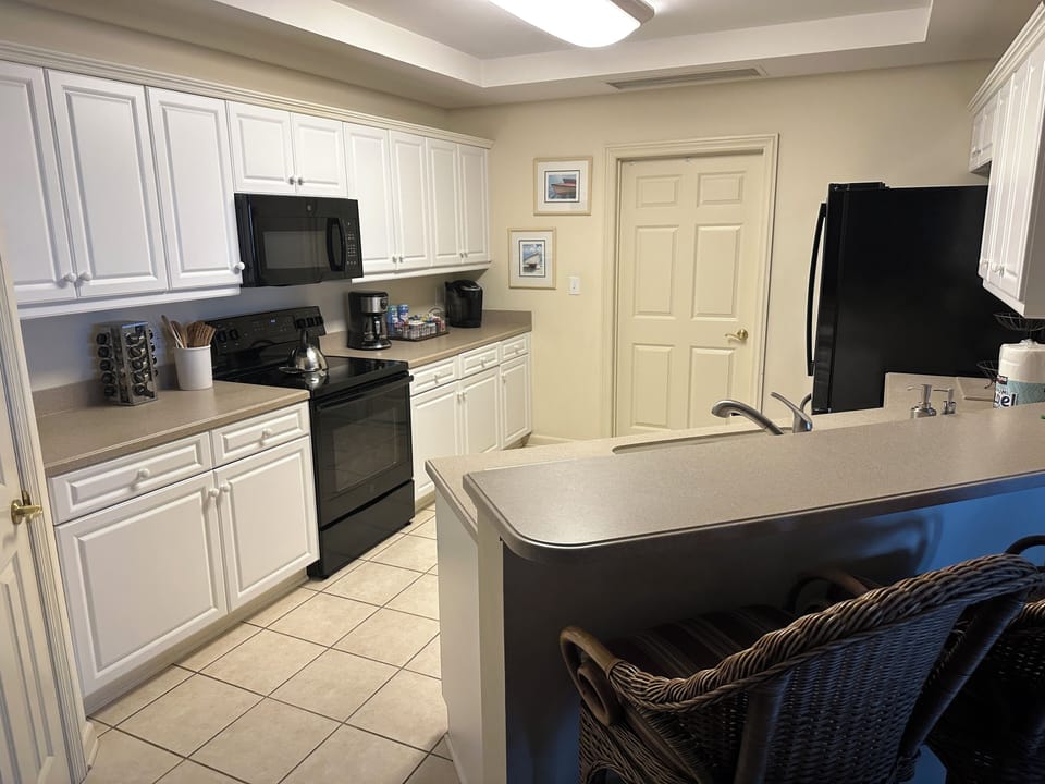Fully equipped spacious kitchen with plentiful dinnerware and utensils.