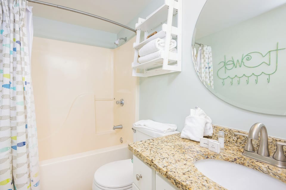 You prepare for a refreshing shower as you reach for plush towels on the bright white shelf above the tub