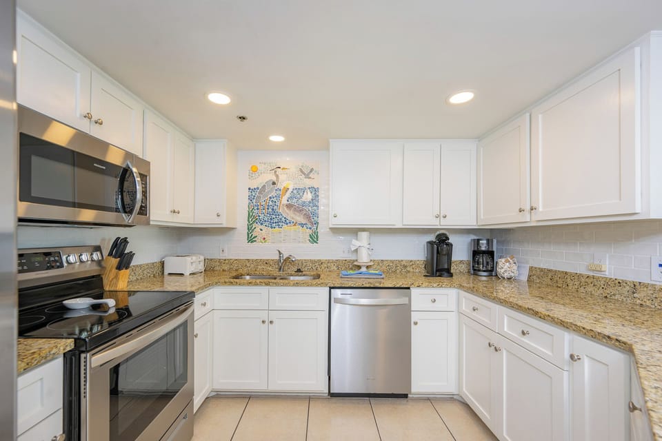 You prepare fresh coastal-inspired dishes in the kitchen surrounded by bright white cabinetry and granite counters