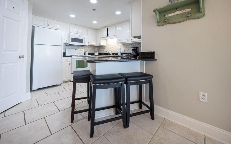 The modern kitchen features a breakfast bar with stylish seating, sleek countertops, and ample cabinetry for storage