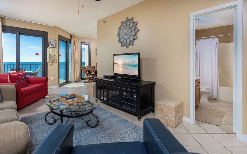 Inviting living space with a large TV, comfortable seating, and views of the tranquil beach beyond