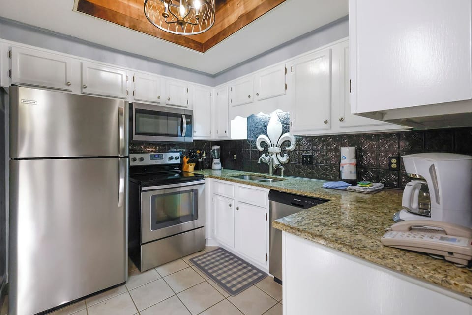 This kitchen features stainless appliances, granite countertops, a stylish backsplash, and a convenient coffee maker