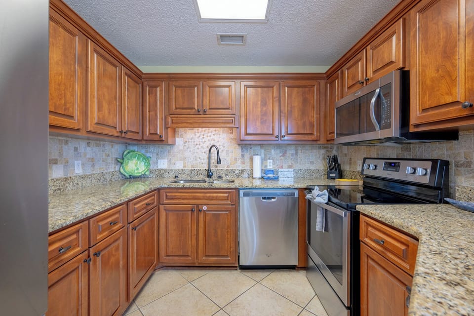 The modern kitchen features rich wood cabinetry, granite countertops, and a convenient breakfast bar with seating