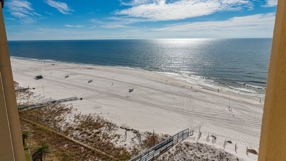 Expansive beachfront view showcasing soft white sand and gentle waves under a clear blue sky, perfect for relaxation