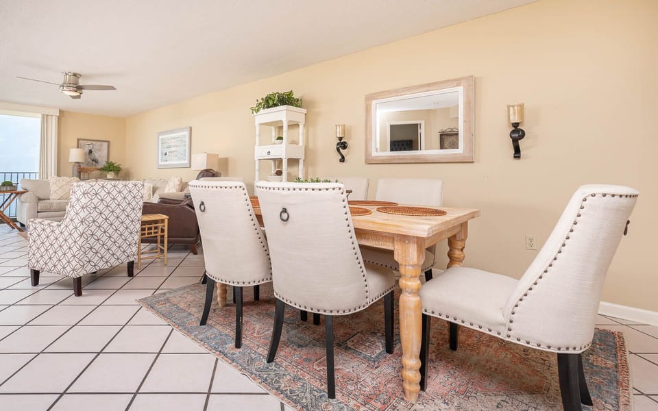 The dining area features a rustic wooden table surrounded by elegant upholstered chairs, creating a welcoming atmosphere
