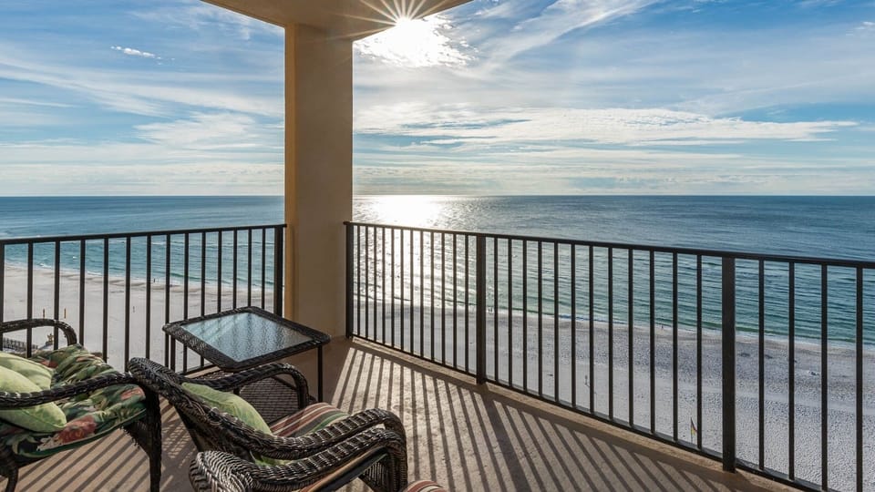 Relax on the balcony with comfortable seating, enjoying the sparkling water and serene beach view just below