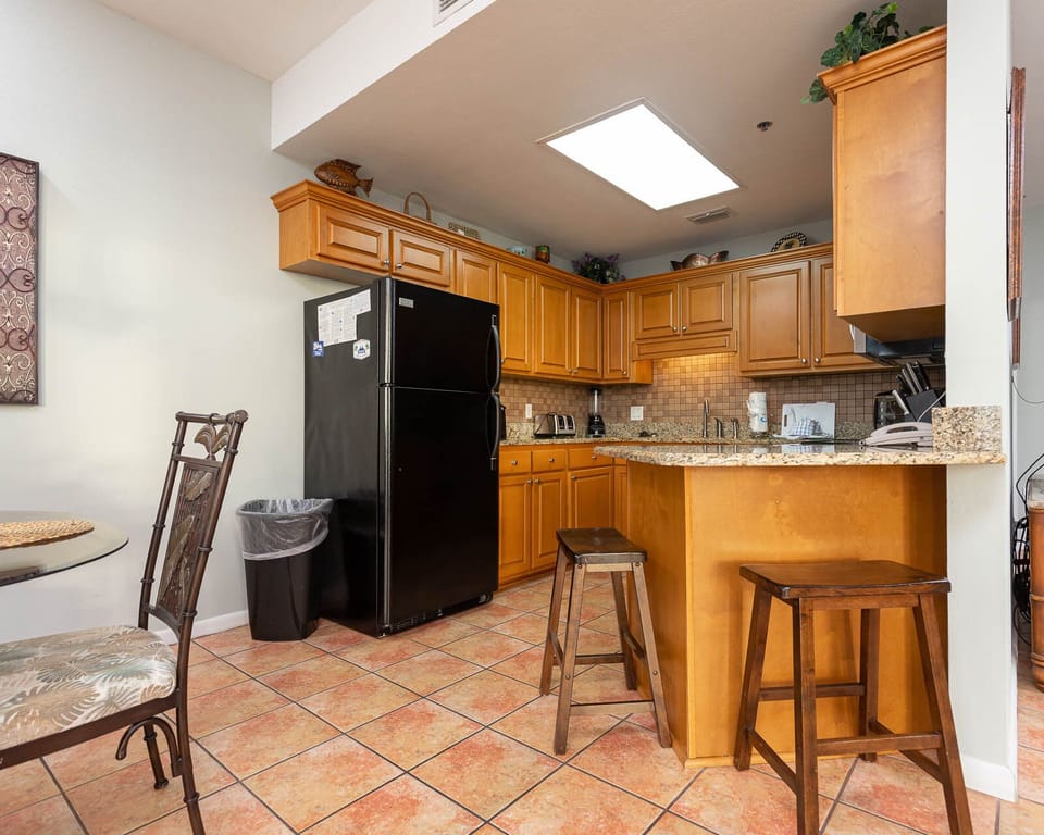 Kitchen with warm wooden cabinetry, a granite countertop breakfast bar with seating, and modern appliances