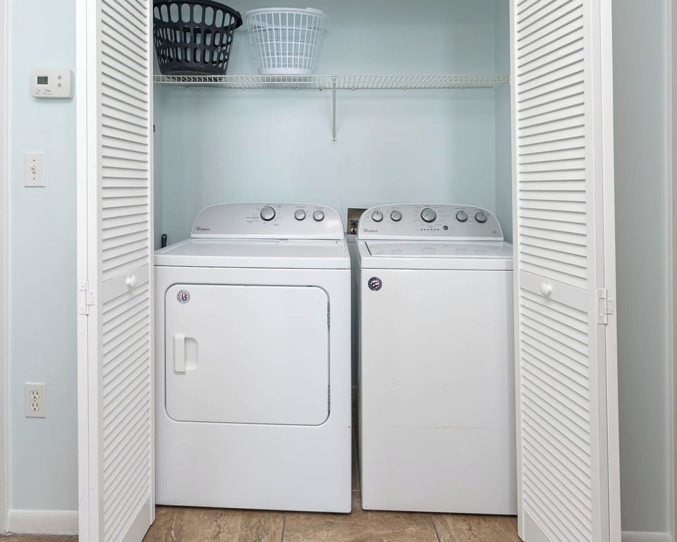 A laundry area features a washer and dryer, with shelves above for storage and baskets, enhancing convenience