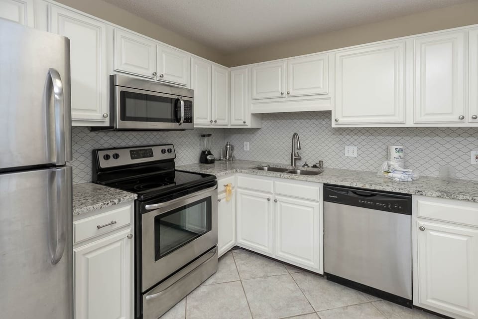 Bright white cabinetry complements the granite countertops in this kitchen, featuring a sleek breakfast bar