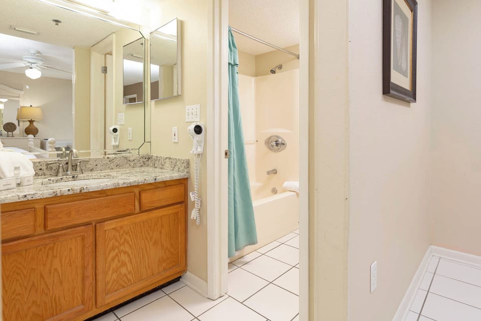 Master bathroom featuring a granite countertop, a tub/shower combo, and a large mirror reflecting the space