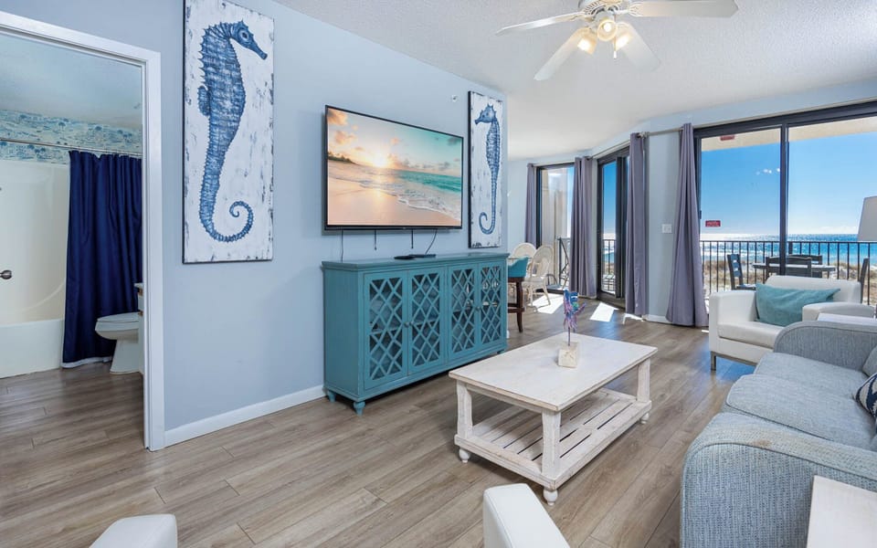 Relax in the living area featuring a TV, coastal decor, sofa with queen sleeper, and beachfront views