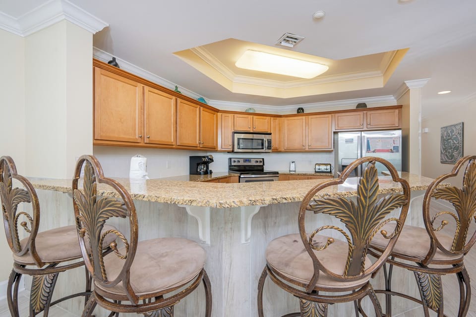Bright kitchen featuring granite countertops, stainless appliances, and elegant bar seating for a welcoming dining experience