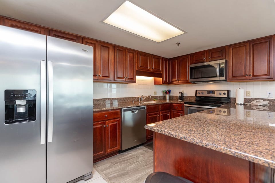 The kitchen features rich wooden cabinetry, a granite countertop, and stainless appliances, creating a functional space