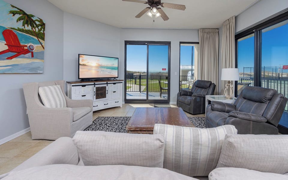 Relax in the inviting living area with comfortable seating, a large TV, and easy access to outdoor patio views