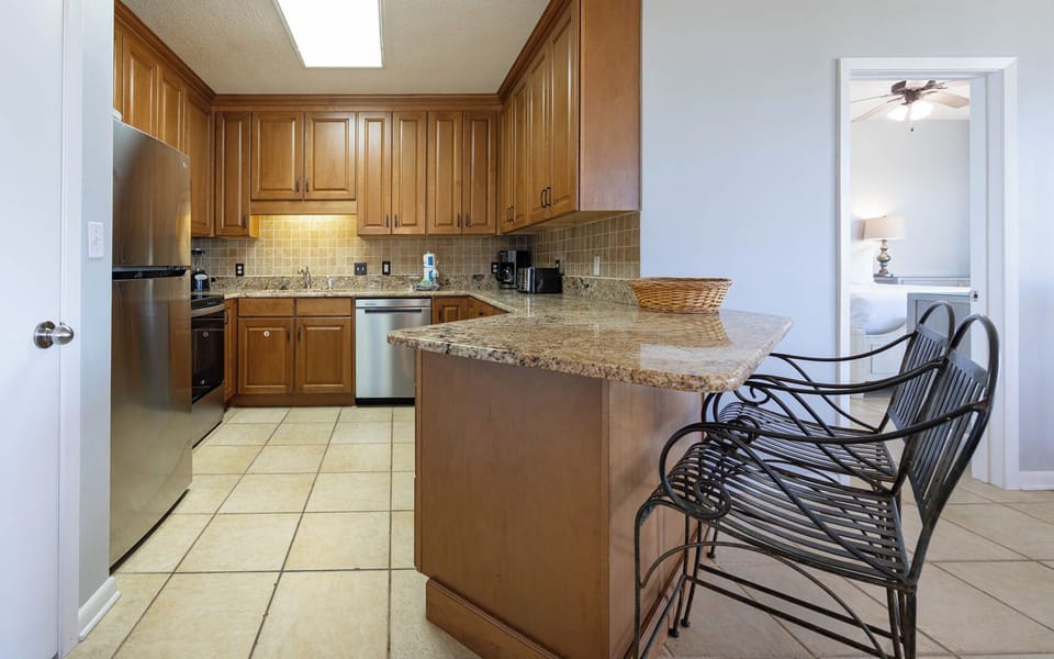 Prepare meals in the spacious kitchen featuring granite countertops and stainless steel appliances, with seating at the bar