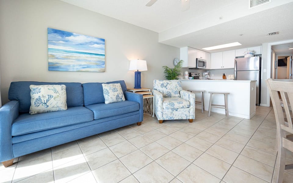 Relax in the inviting living area with comfortable seating, coastal decor, and easy access to the kitchen