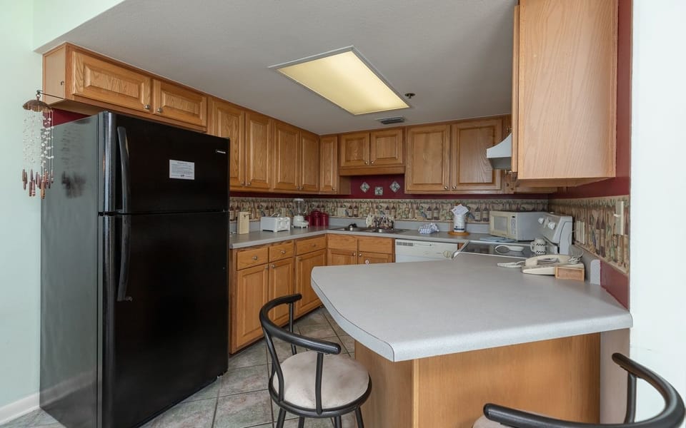 Prepare meals in this kitchen, featuring ample cabinetry with black and white appliances