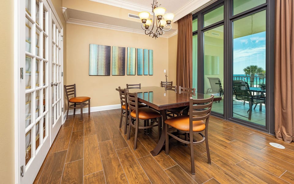 Gather around the dining table in this cozy room where sunlight filters through glass doors to the balcony