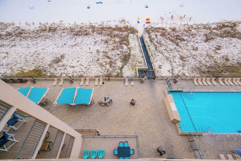 Bright poolside scene invites you to relax under blue canopies while kids splash nearby