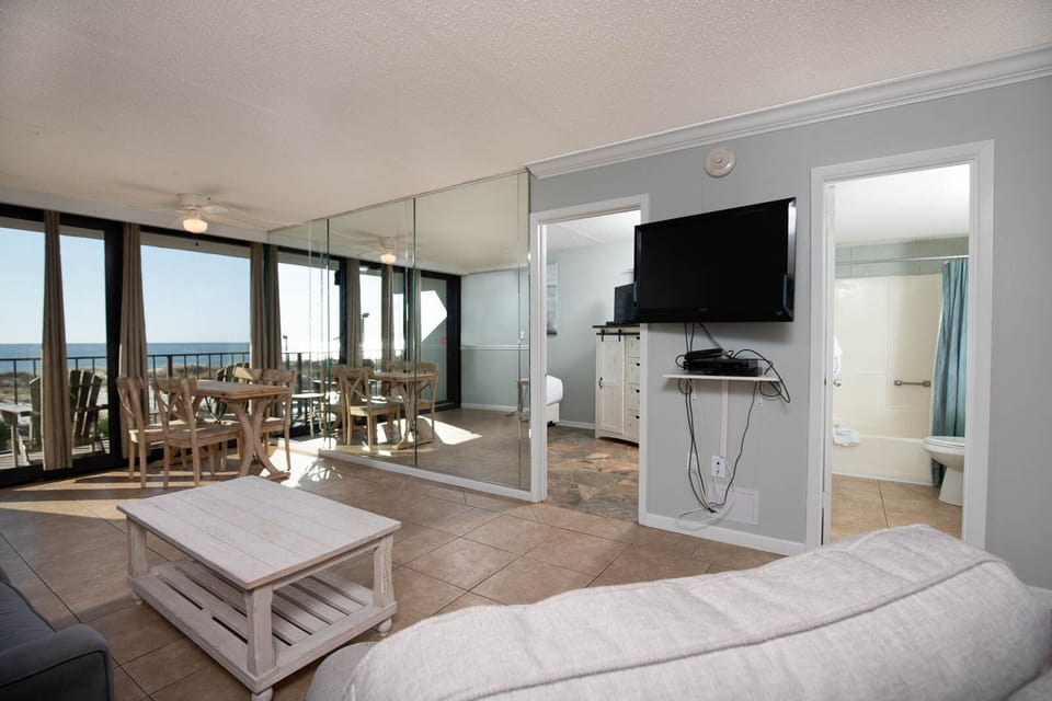 This inviting space features a cozy seating area with a view of the beach and a dining table perfect for meals