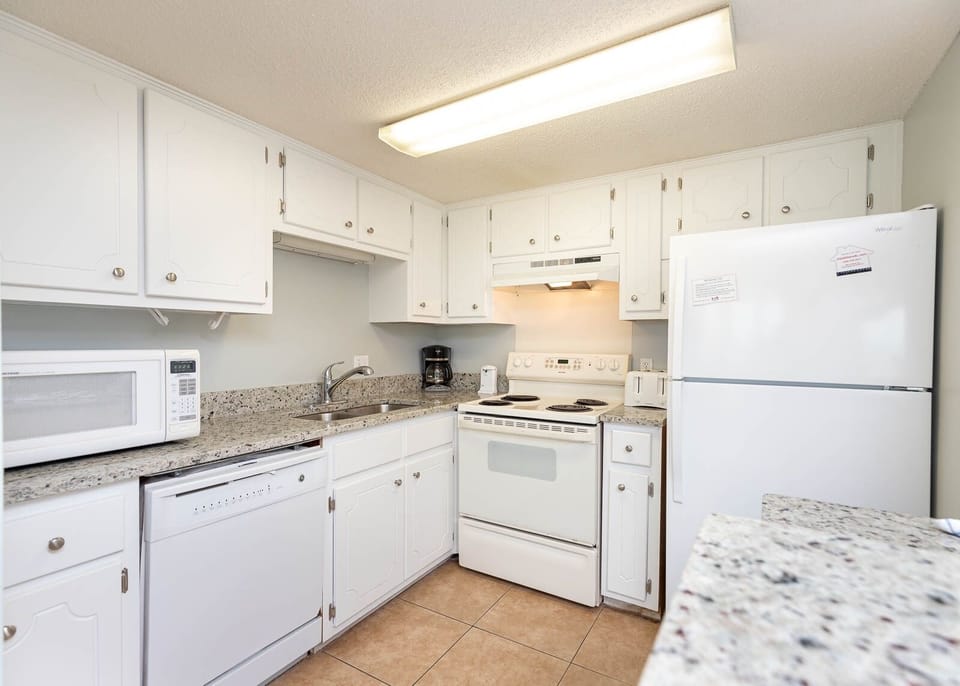 This kitchen features white cabinetry, granite countertops, and essential appliances for a delightful cooking experience