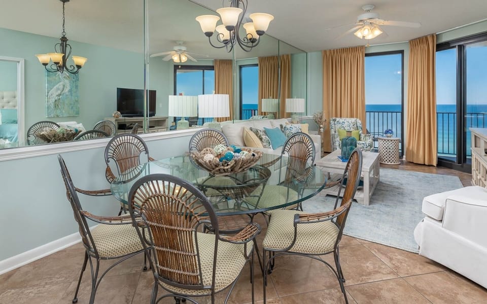 Dine at the glass table surrounded by stylish chairs, with a cozy living area and beautiful views just beyond