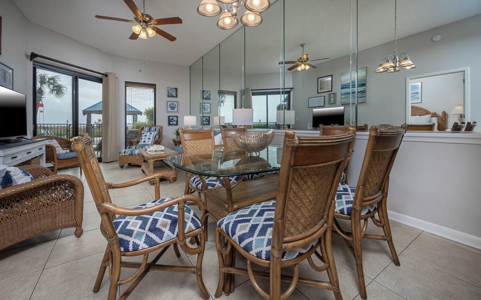 Enjoy meals at the glass dining table surrounded by comfortable rattan chairs, with a view of the beachfront patio