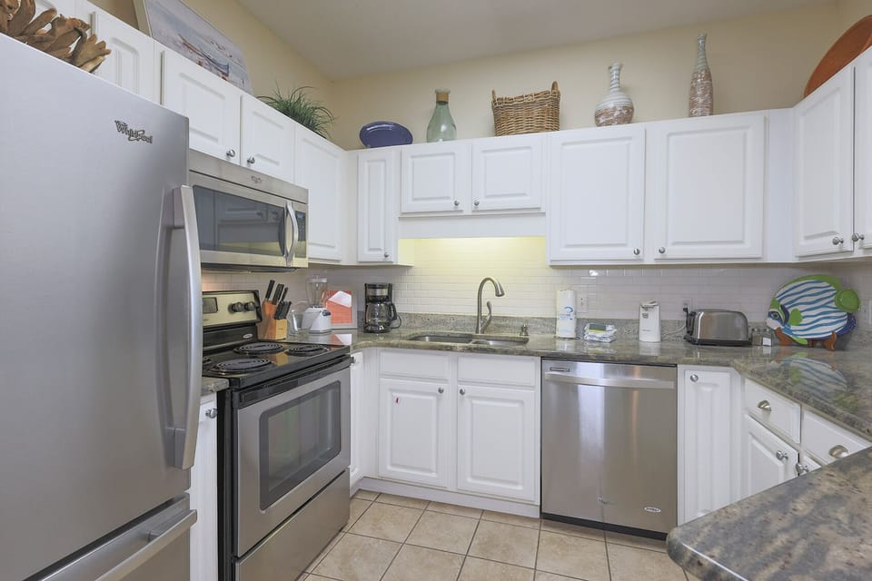 Bright white cabinetry complements the stylish countertops in this kitchen, featuring stainless appliances