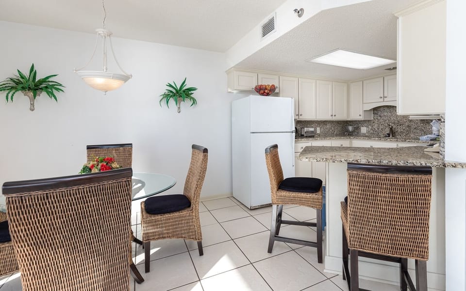 Bright dining area featuring a glass table with chairs, complemented by a modern breakfast bar and stylish decor