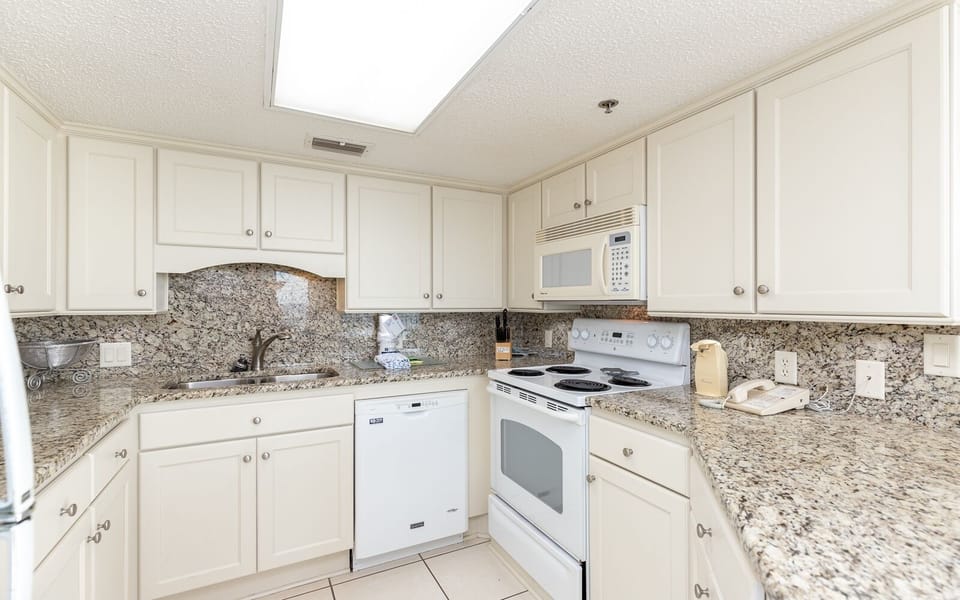 Bright kitchen featuring white cabinetry, stylish countertops, and essential appliances for a convenient cooking experience