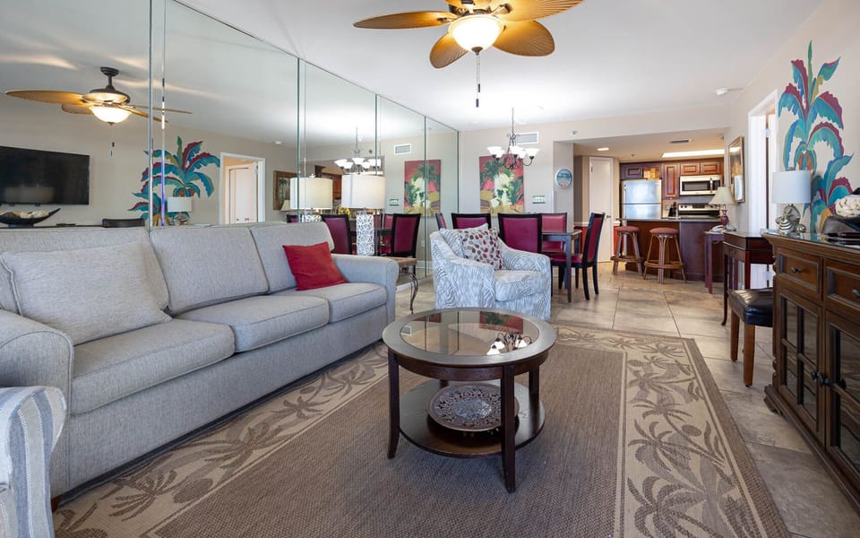 Living area features a comfortable gray sofa, stylish chairs, and a dining space with colorful artwork and a breakfast bar