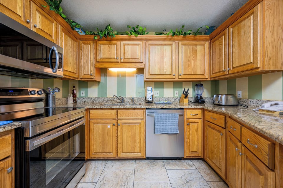 Cook meals in this stylish kitchen featuring granite countertops, wooden cabinetry, and stainless appliances