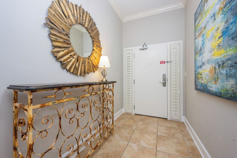 Bright and welcoming entryway featuring a stylish gold mirror, elegant console table, and vibrant artwork