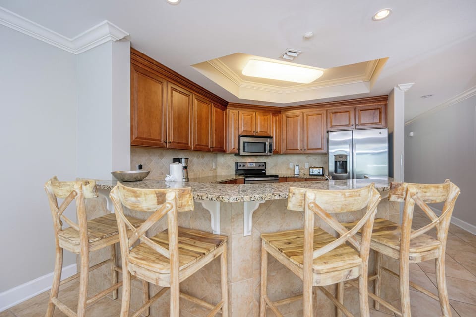Inviting kitchen with granite countertops, stainless appliances, and rustic wooden bar stools for casual dining