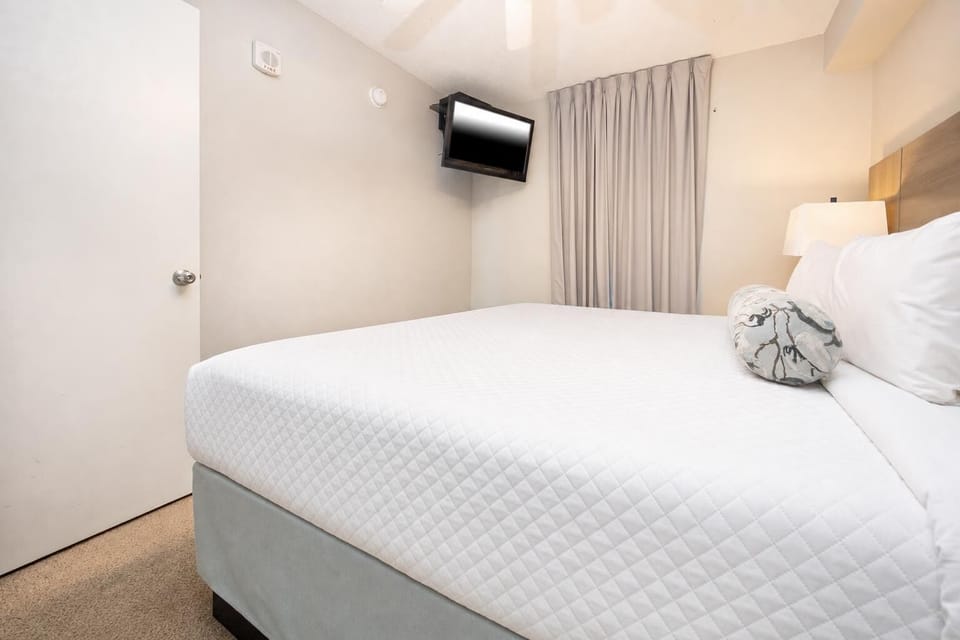 Discover this inviting bedroom featuring a cozy king bed, mounted TV, and soft lighting for a restful stay