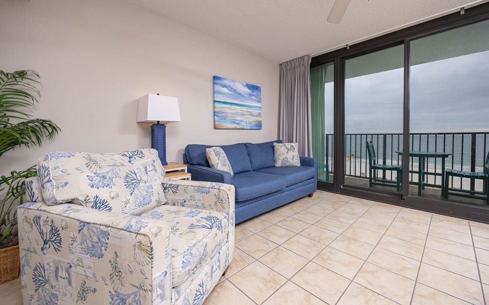 Living area featuring a plush sofa, decorative armchair, and easy access to the outdoor seating