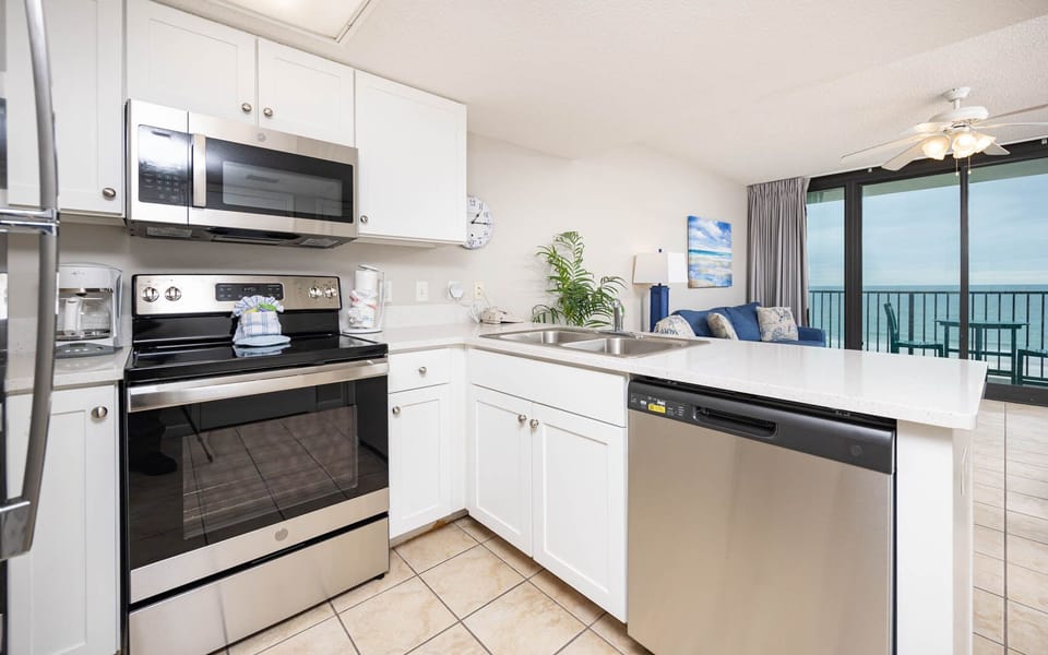 Prepare meals in the sleek kitchen with stainless steel appliances, white cabinetry, and views of the inviting living space