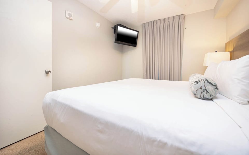 Discover this inviting bedroom featuring a cozy king bed, mounted TV, and soft lighting for a restful stay