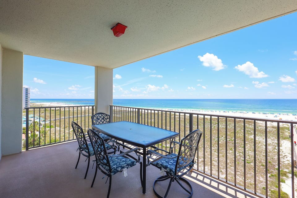 Spacious balcony with a dining table and chairs offers a direct view of the beach and the tranquil Gulf waters