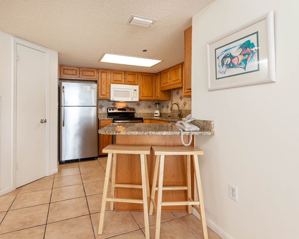 Gather around the breakfast bar with stools, enjoying the warm wood tones and granite countertops in this inviting kitchen