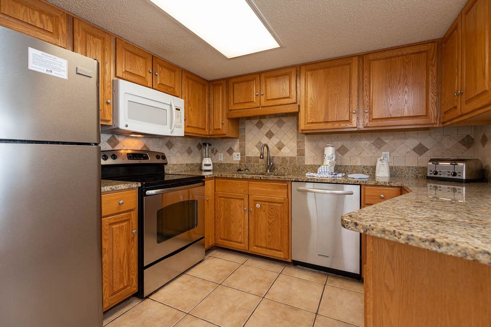 Prepare meals in the spacious kitchen featuring essential appliances, ample counter space, and warm wood cabinetry