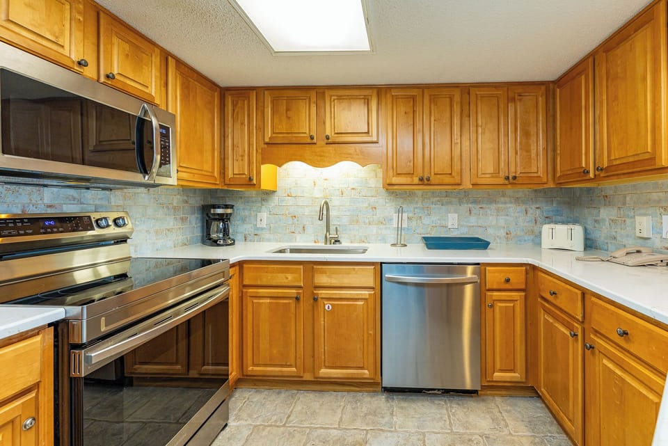 Warm wood cabinetry complements the modern appliances in this inviting kitchen, featuring ample counter space for meal prep