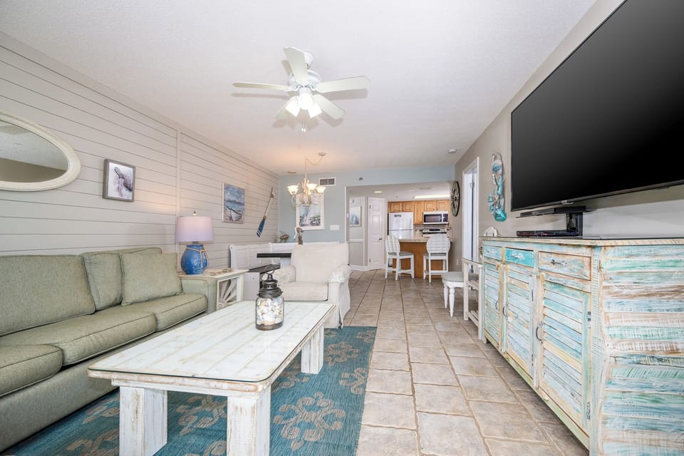 Living area features a green sofa, decorative accents, and a view toward the dining space and modern kitchen beyond