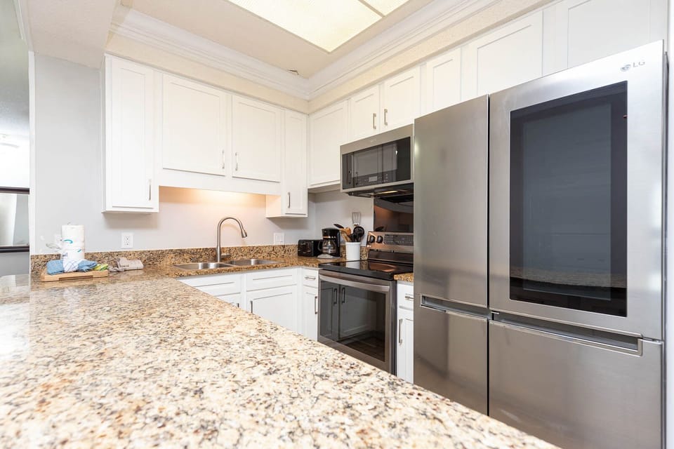 This kitchen features modern stainless appliances, granite countertops, and a convenient coffee maker for your morning brew