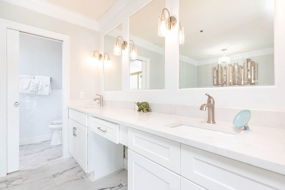 The master bath features elegant dual sinks, a large vanity, jetted tub with a beach view, and stylish walk-in shower