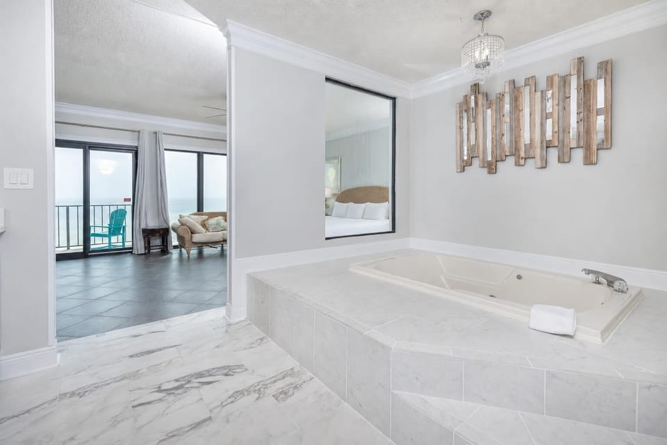 This elegant bathroom features a jetted tub with a view of the bedroom and private balcony that overlooks the beach